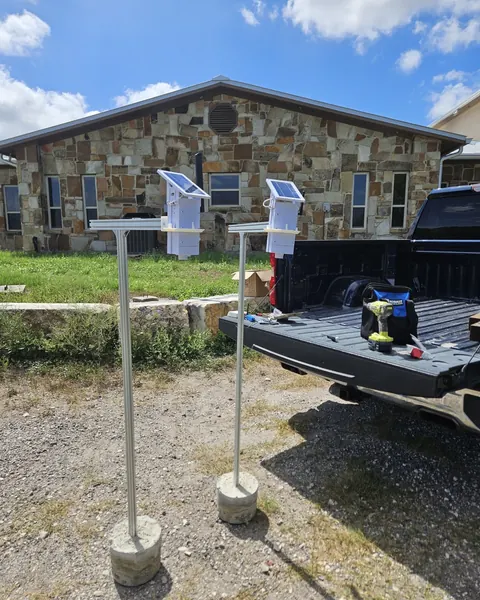 Two Trivertix pilot units on poles with concrete bases, beside a pickup tailgate with tools