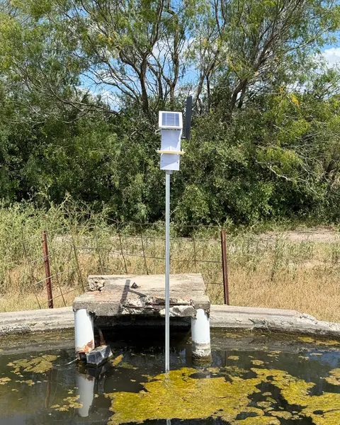 A Trivertix monitor with its antenna, on a pole standing in a stock tank